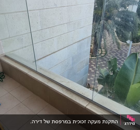 מעקה זכוכית במרפסת עם קיר אבן